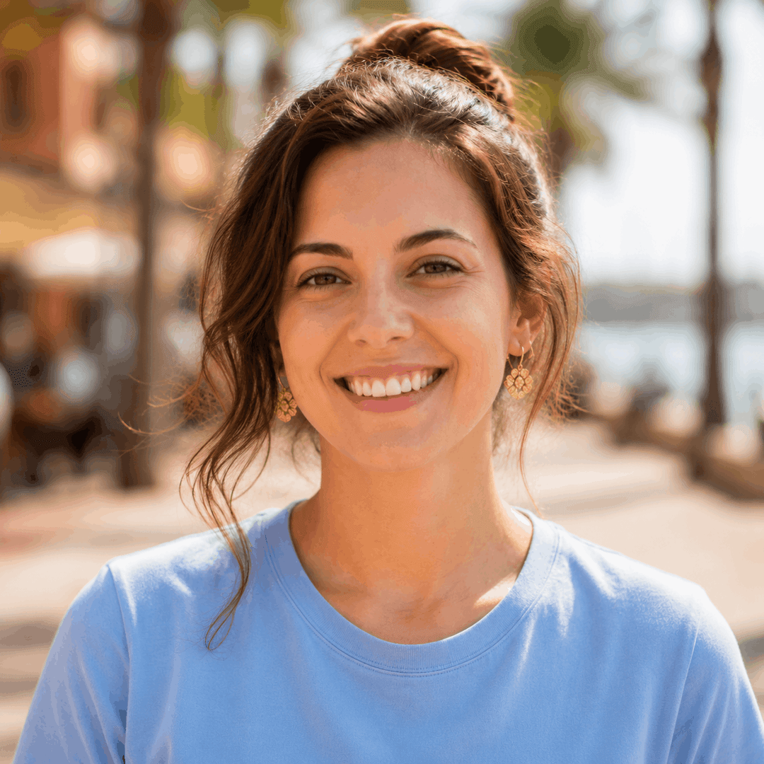 A woman smiling outdoors on a sunny street.